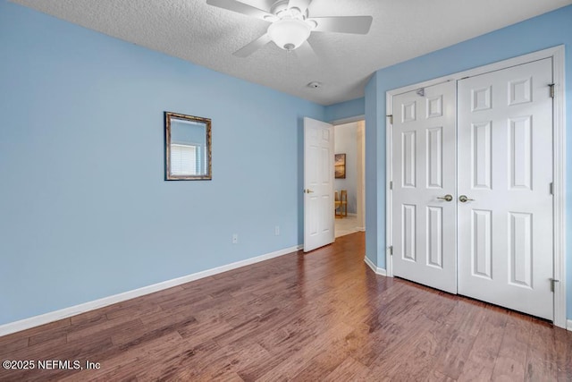 unfurnished bedroom featuring hardwood / wood-style flooring, a textured ceiling, ceiling fan, and a closet