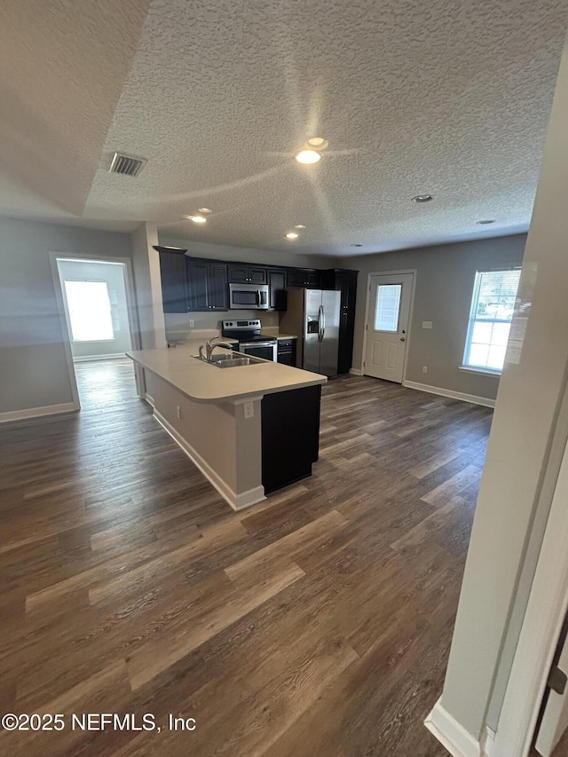 kitchen featuring dark wood-type flooring, stainless steel appliances, kitchen peninsula, and a breakfast bar area