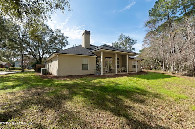 back of property with central AC unit and a lawn