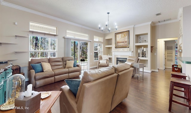 living room featuring dark hardwood / wood-style floors, a chandelier, crown molding, a textured ceiling, and built in shelves