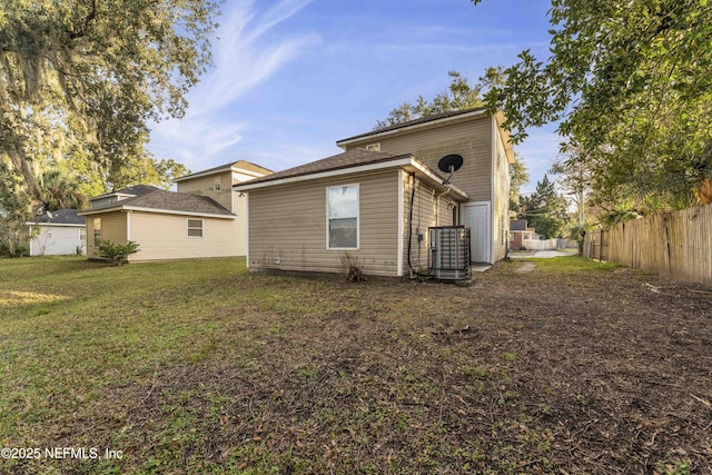 rear view of property with central AC unit and a yard