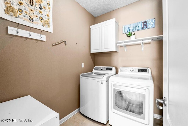 laundry room with cabinets, washing machine and dryer, and a textured ceiling