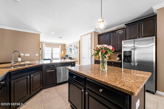 kitchen featuring sink, stainless steel appliances, light stone counters, a kitchen island, and decorative light fixtures