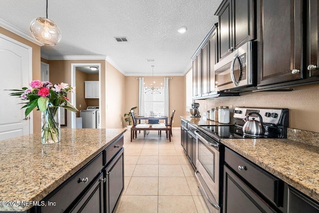 kitchen with pendant lighting, appliances with stainless steel finishes, washer / clothes dryer, and light stone counters