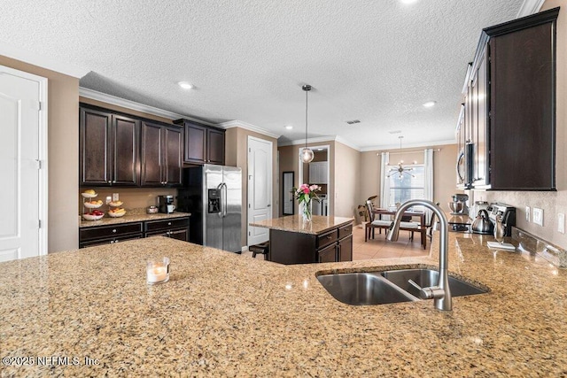 kitchen with dark brown cabinetry, sink, decorative light fixtures, appliances with stainless steel finishes, and a kitchen island