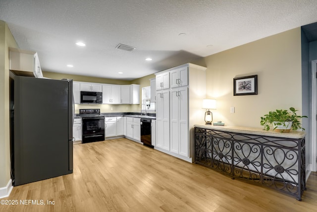 54110 Marlee Rd, Callahan, FL 32011 - kitchen featuring a textured ceiling, light hardwood / wood-style flooring, black appliances, and white cabinets