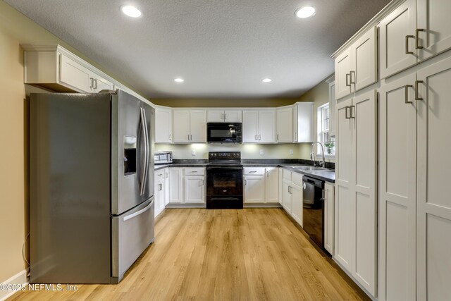 54110 Marlee Rd, Callahan, FL 32011 - kitchen featuring sink, black appliances, light hardwood / wood-style floors, a textured ceiling, and white cabinets