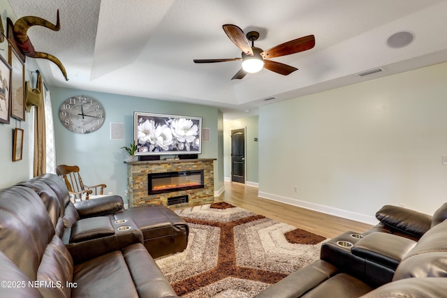 54110 Marlee Rd, Callahan, FL 32011 - living room with a stone fireplace, ceiling fan, light hardwood / wood-style floors, a raised ceiling, and a textured ceiling