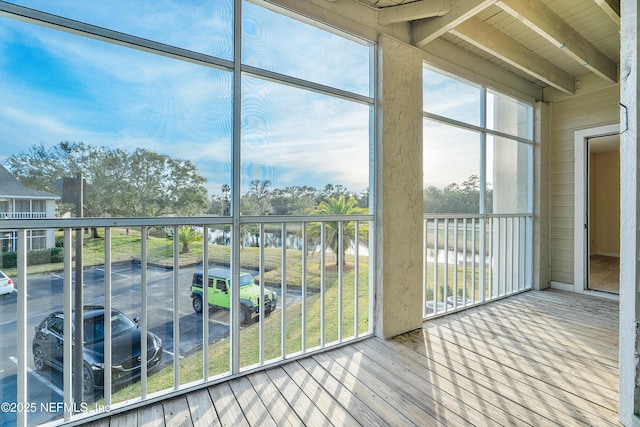 unfurnished sunroom featuring beam ceiling and a water view