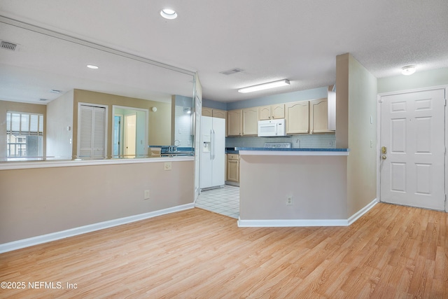 kitchen with light hardwood / wood-style floors, light brown cabinets, white appliances, and kitchen peninsula