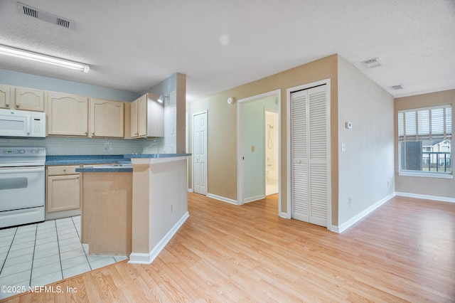 kitchen with white appliances, light brown cabinetry, light hardwood / wood-style floors, and decorative backsplash