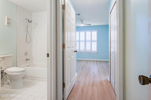 bathroom featuring ceiling fan, tiled shower / bath combo, tile patterned floors, and toilet