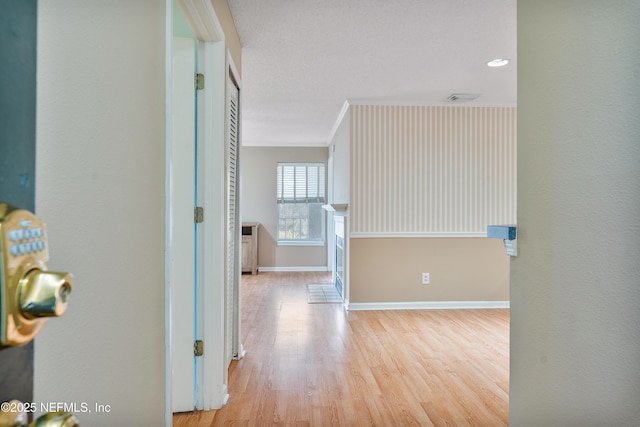 hallway with crown molding and light wood-type flooring