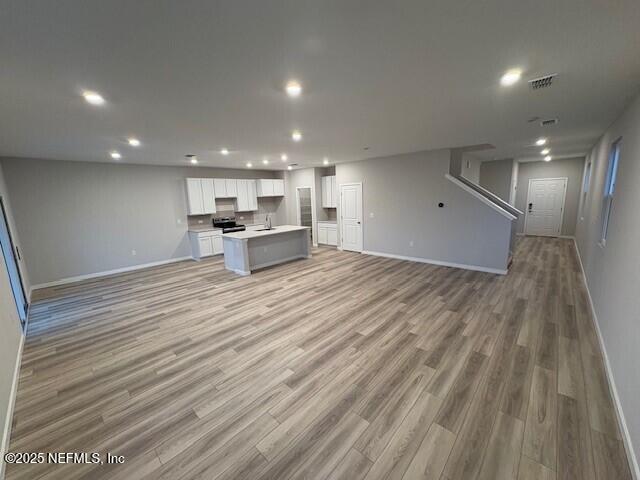 unfurnished living room with sink and light wood-type flooring