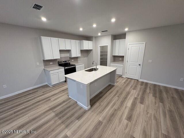 kitchen featuring white cabinetry, a kitchen island with sink, sink, and stainless steel range with electric cooktop