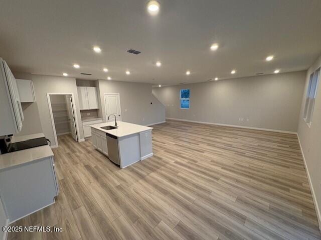 kitchen with white cabinetry, light hardwood / wood-style flooring, an island with sink, and dishwasher