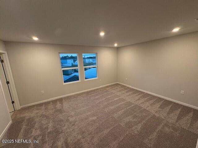 spare room featuring dark colored carpet