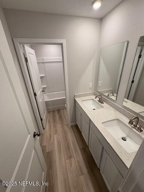 bathroom with wood-type flooring, bathing tub / shower combination, vanity, and a textured ceiling