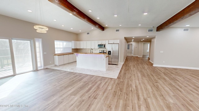 kitchen featuring white cabinetry, backsplash, a center island, stainless steel appliances, and beam ceiling