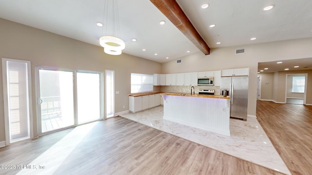 kitchen with appliances with stainless steel finishes, white cabinetry, sink, backsplash, and hanging light fixtures