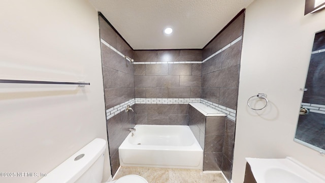 bathroom with tiled shower / bath combo, a textured ceiling, and toilet