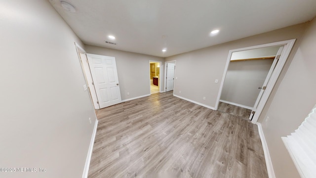 unfurnished bedroom with light hardwood / wood-style flooring and a closet