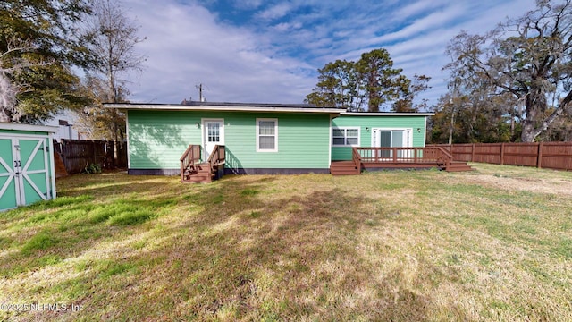 back of property with a wooden deck, a yard, and a storage unit