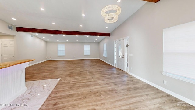 unfurnished living room with lofted ceiling with beams, light hardwood / wood-style floors, and a notable chandelier