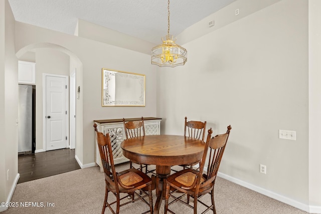 carpeted dining room with a textured ceiling