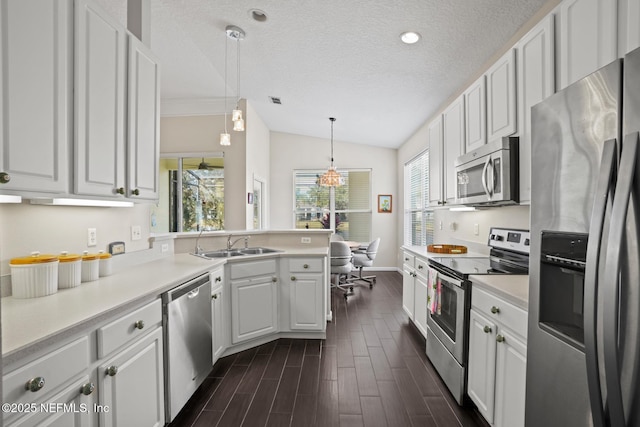 kitchen with white cabinetry, decorative light fixtures, vaulted ceiling, a textured ceiling, and appliances with stainless steel finishes