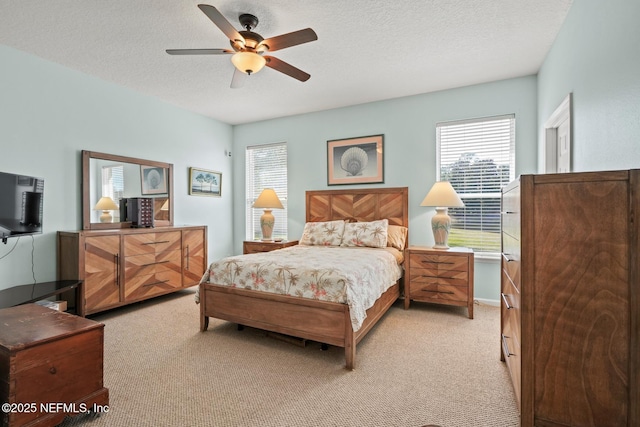 carpeted bedroom featuring multiple windows, a textured ceiling, and ceiling fan