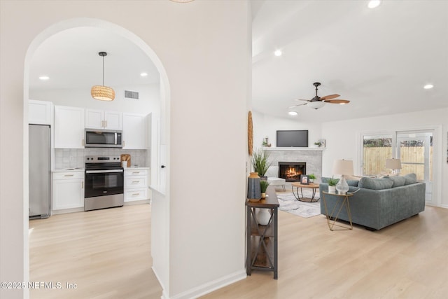 living room with light hardwood / wood-style flooring, ceiling fan, and vaulted ceiling