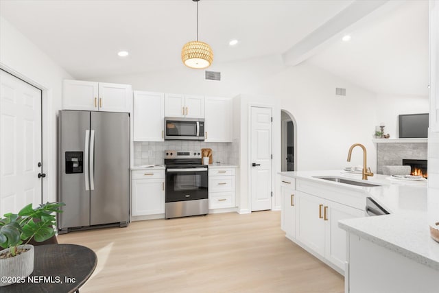 kitchen featuring stainless steel appliances, white cabinetry, hanging light fixtures, and sink