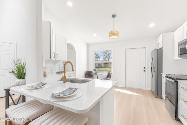 kitchen featuring appliances with stainless steel finishes, decorative light fixtures, white cabinetry, sink, and kitchen peninsula