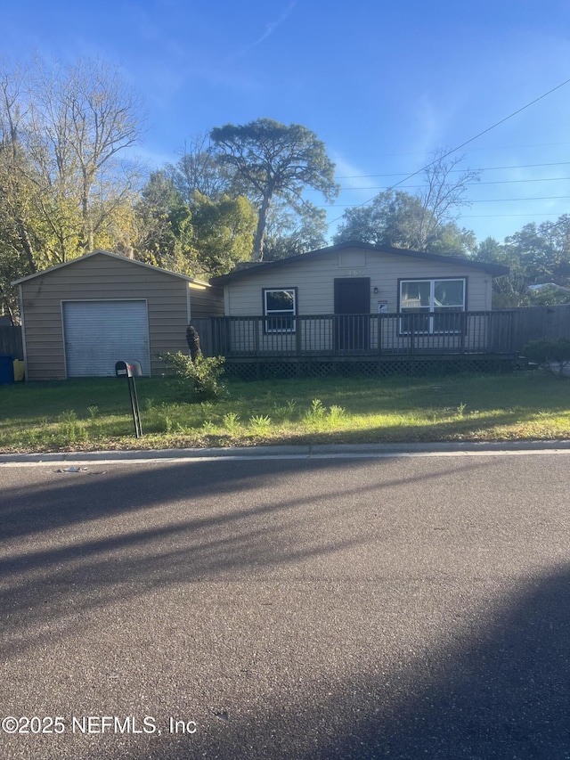 view of front facade featuring a garage, a wooden deck, an outdoor structure, and a front yard