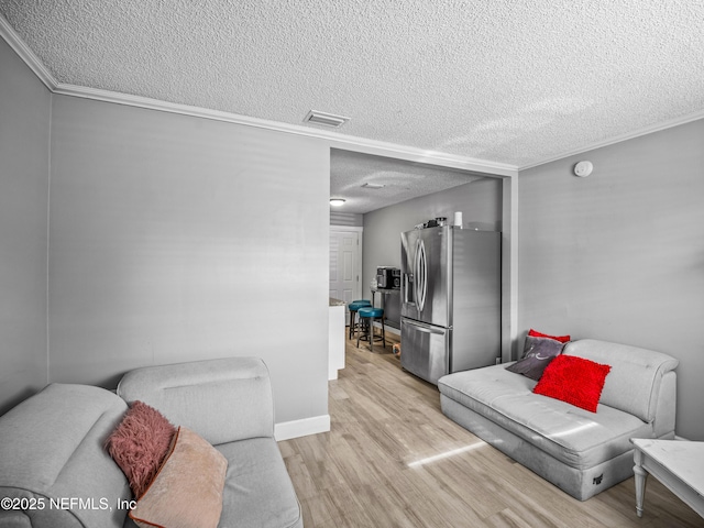 living room featuring crown molding, light hardwood / wood-style flooring, and a textured ceiling