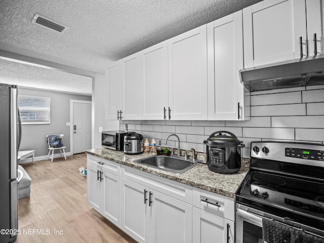 kitchen featuring light stone countertops, stainless steel appliances, and white cabinets