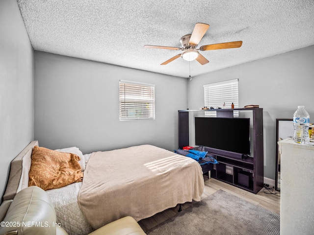 bedroom featuring ceiling fan, light hardwood / wood-style floors, and a textured ceiling