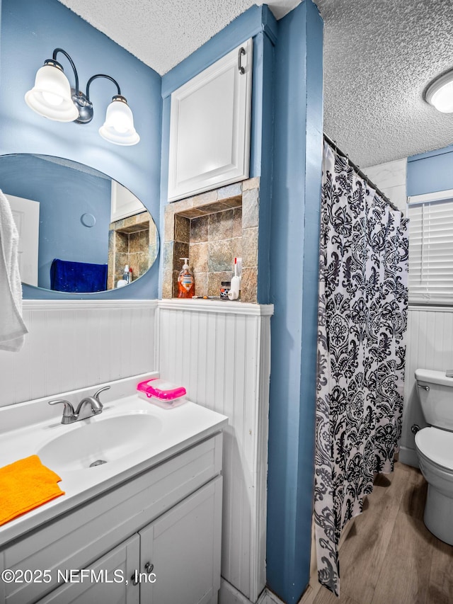 bathroom with hardwood / wood-style flooring, vanity, a textured ceiling, a shower with curtain, and toilet