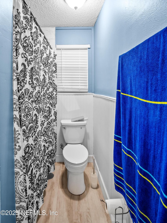 bathroom with wood-type flooring, toilet, and a textured ceiling