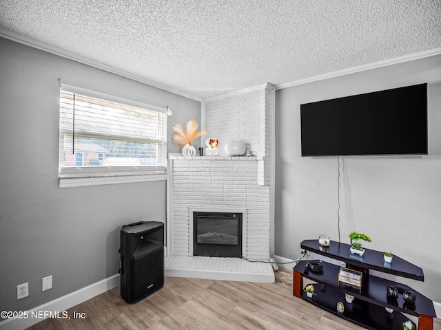 living room with hardwood / wood-style floors, a fireplace, ornamental molding, and a textured ceiling