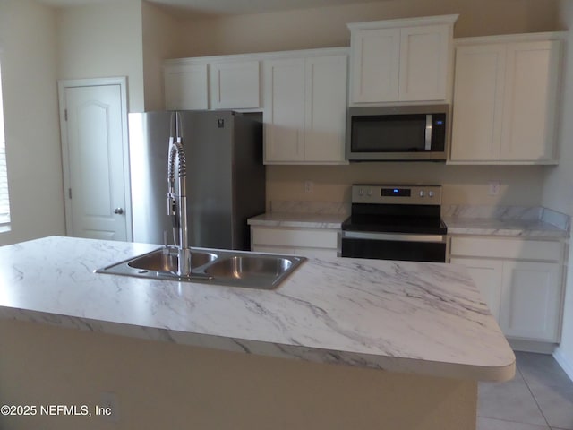 kitchen featuring stainless steel appliances, sink, a center island with sink, and white cabinets