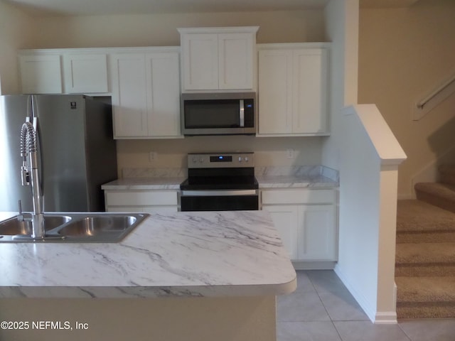 kitchen featuring appliances with stainless steel finishes, light tile patterned floors, and white cabinets