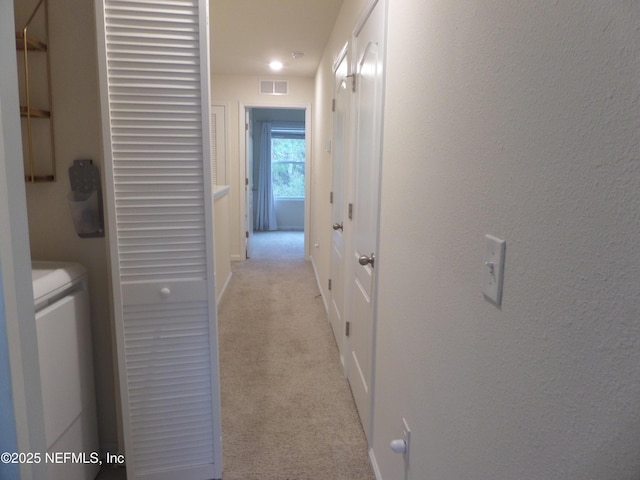 hall featuring light colored carpet and independent washer and dryer