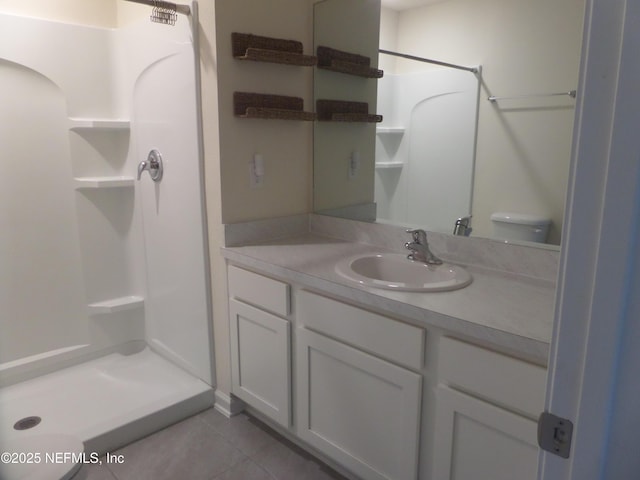 bathroom featuring vanity, toilet, tile patterned flooring, and a shower