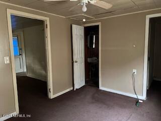 unfurnished bedroom with ceiling fan and dark colored carpet