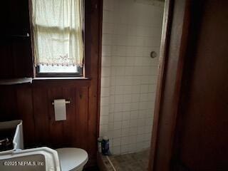 bathroom featuring tiled shower and toilet