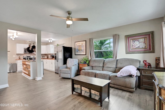 living room with ceiling fan, sink, and light hardwood / wood-style flooring