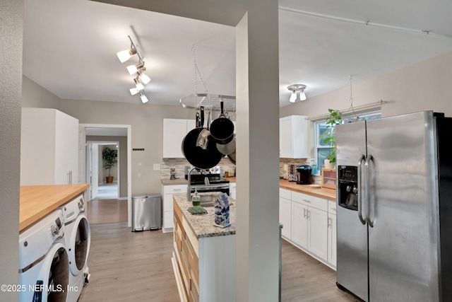 kitchen featuring tasteful backsplash, white cabinetry, appliances with stainless steel finishes, and washer and dryer