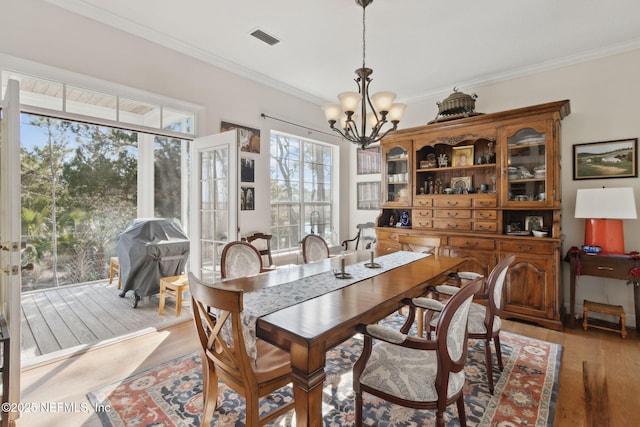 dining space featuring crown molding, a chandelier, and light hardwood / wood-style floors